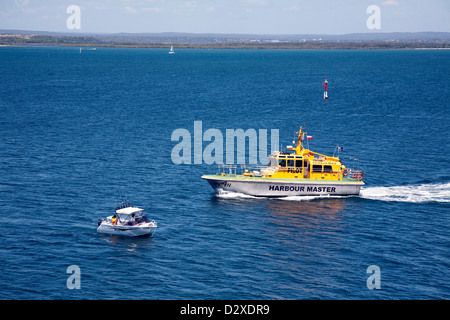 Port Botany Pilot Boat warning fishermen in a small boat of approaching shipping container ship Sydney Australia Stock Photo