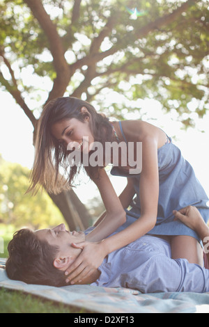 Affectionate couple on blanket in grass under tree Stock Photo