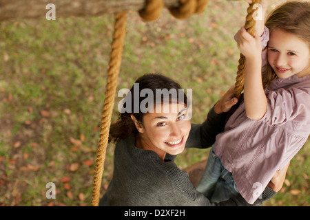 Portrait of smiling mother and daughter on swing Stock Photo