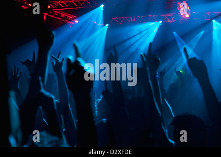 Silhouette of crowd cheering with arms raised at concert Stock Photo