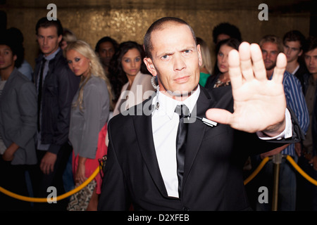 Portrait of bouncer with arm outstretched outside nightclub Stock Photo