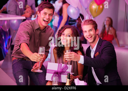 Portrait of enthusiastic friends with champagne and gift Stock Photo