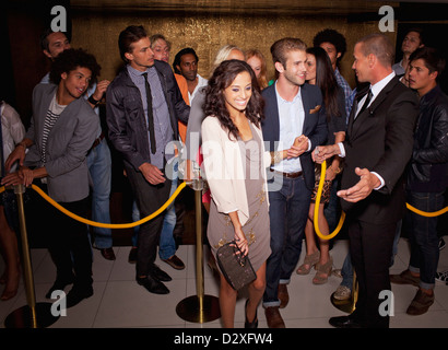 Bouncer granting couple access outside nightclub Stock Photo