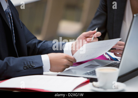 Close up of business people reviewing paperwork at cafe Stock Photo