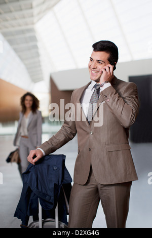 Smiling businessman talking on cell phone at airport Stock Photo