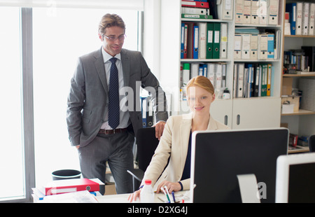 Businessman and businesswoman using computer at desk in office Stock Photo