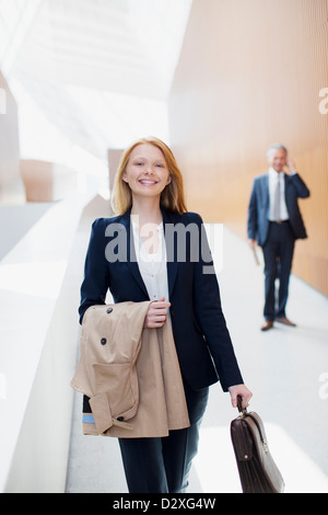 Portrait of smiling businesswoman with coat and briefcase Stock Photo