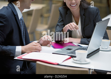 Smiling businessman and businesswoman using laptop in cafe Stock Photo