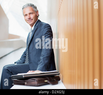 Portrait of smiling businessman with laptop and briefcase Stock Photo