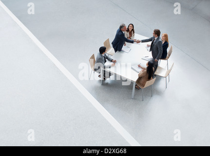 Businessmen in meeting shaking hands across table Stock Photo