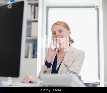 Portrait of confident businesswoman using computer and talking on telephone Stock Photo