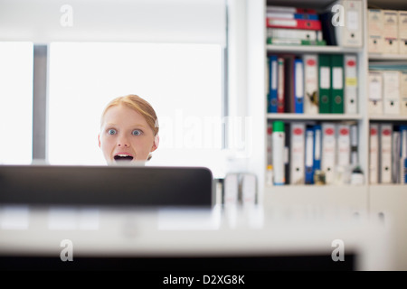 Surprised businesswoman reading e-mail at computer in office Stock Photo