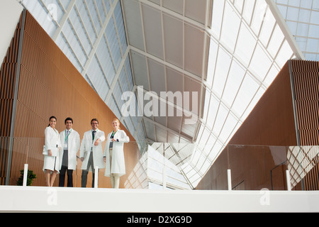 Portrait of smiling doctors at glass railing of balcony in modern building Stock Photo