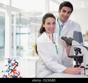 Portrait of smiling scientists using microscope in laboratory Stock Photo
