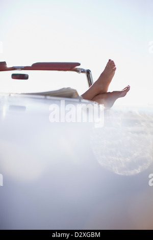 Woman’s feet resting on convertible Stock Photo