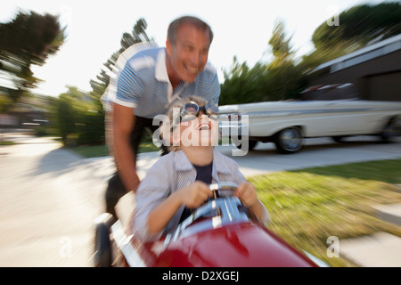 Time lapse view of father pushing son in go cart Stock Photo