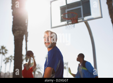 Older men playing basketball on court Stock Photo