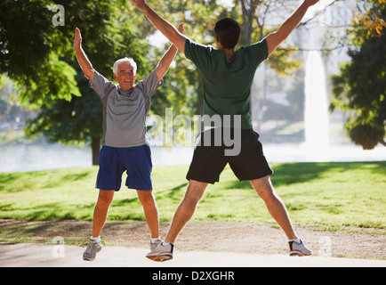 Older men doing jumping jacks outdoors Stock Photo