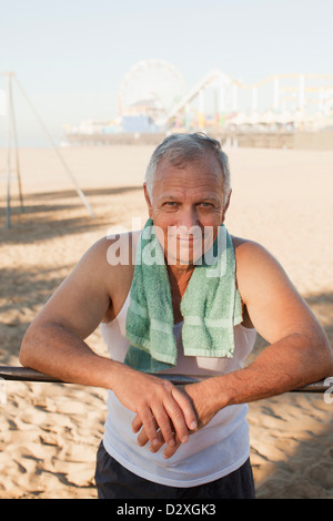 Older man relaxing after workout on beach Stock Photo