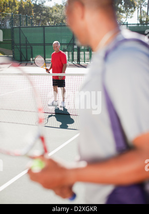 Older men playing tennis on court Stock Photo