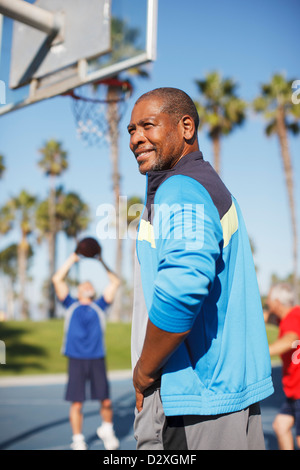 Older man playing basketball on court Stock Photo