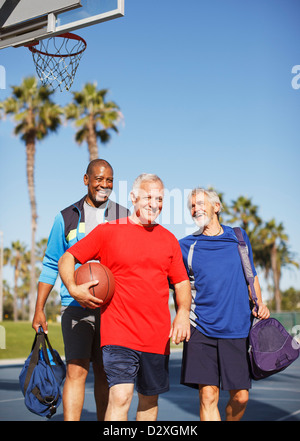 Older men playing basketball on court Stock Photo