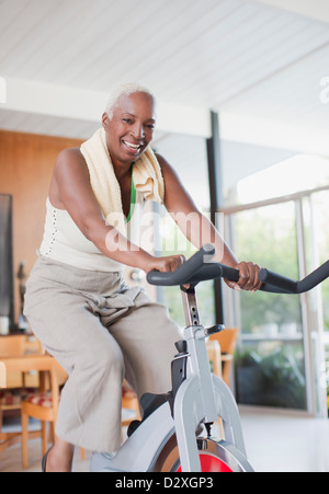 Older woman using exercise bike in home Stock Photo