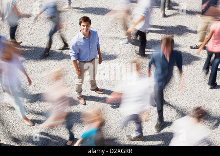 Portrait of smiling businessman surrounded by people rushing by Stock Photo