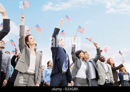Smiling business people in crowd waving American flags Stock Photo