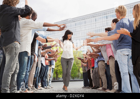 Woman touching hands of fans in crowd Stock Photo