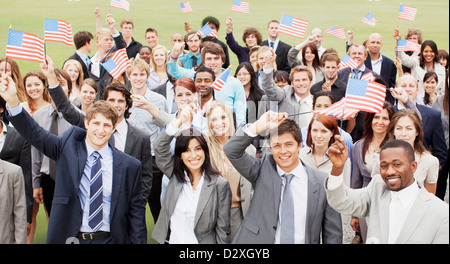 Portrait of smiling business people waving American flags overhead Stock Photo