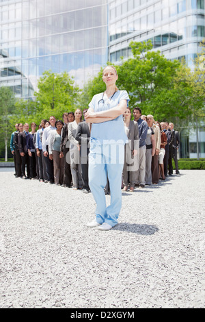 Portrait of confident nurse with business people in background Stock Photo