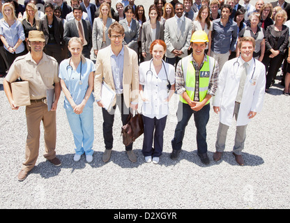 Portrait of smiling professionals and workers with business people in background Stock Photo