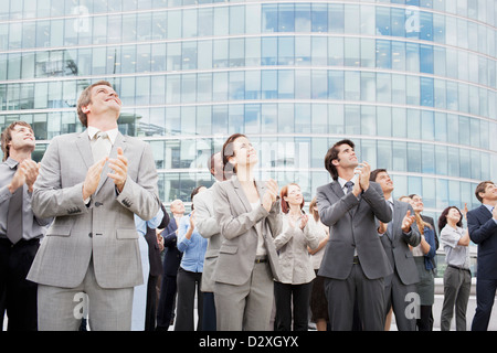 Smiling business people clapping and looking up Stock Photo