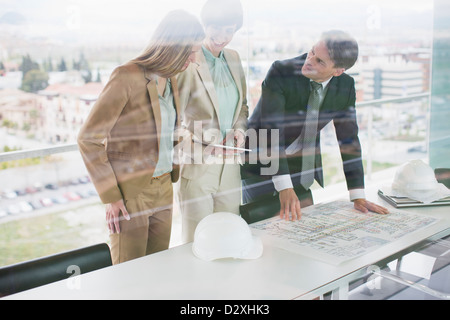 Architects with digital tablet reviewing blueprints in office Stock Photo