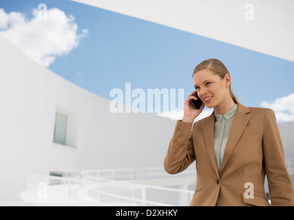 Smiling businesswoman talking on cell phone in courtyard Stock Photo