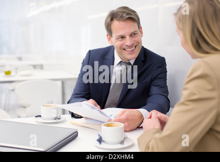 Smiling business people discussing paperwork in cafe Stock Photo
