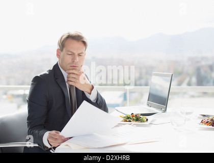 Businessman with lunch reviewing paperwork Stock Photo