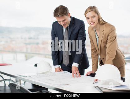 Architects reviewing blueprints at desk Stock Photo