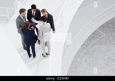 Business people reviewing paperwork on elevated walkway Stock Photo