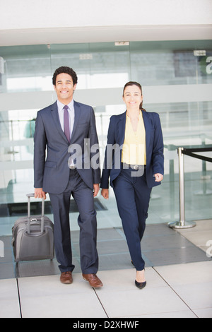 Portrait of smiling businessman and businesswoman with suitcase at airport Stock Photo
