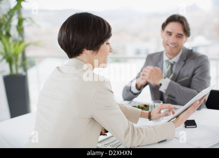 Businessman and businesswoman using digital tablet at restaurant table Stock Photo