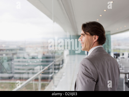 Smiling businessman looking out window of conference room Stock Photo