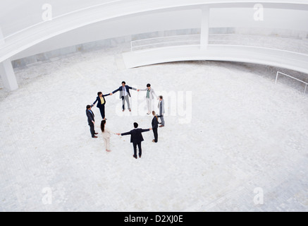 Business people holding hands in circle in courtyard Stock Photo