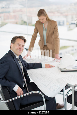 Portrait of confident architect reviewing blueprints with co-worker Stock Photo