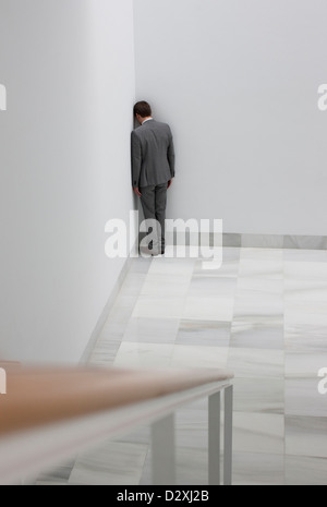 Dejected businessman standing in corner Stock Photo