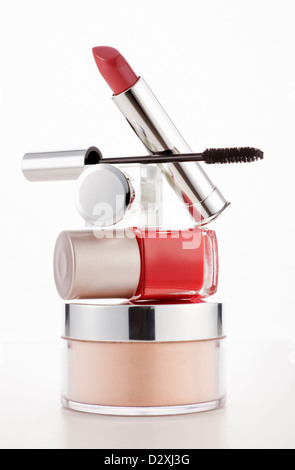 Lipstick, mascara and fingernail polish stacked on moisturizer jar Stock Photo