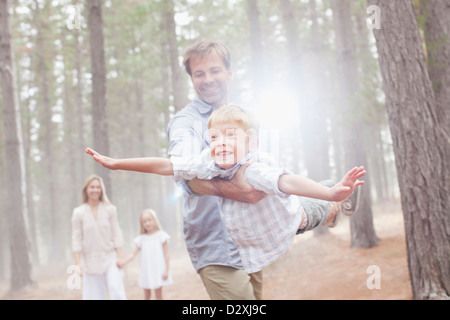 Father flying son in sunny woods Stock Photo