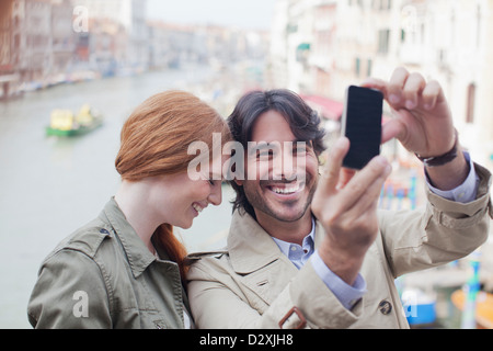 Laughing couple taking self-portrait with camera phone on canal in Venice Stock Photo