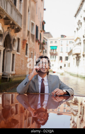 Smiling businessman talking on cell phone and riding boat through canal in Venice Stock Photo